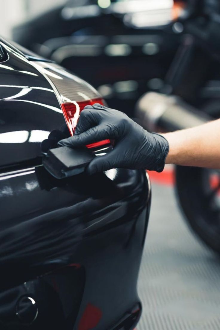 Detailer applying finishing product by hand on a dark vehicle