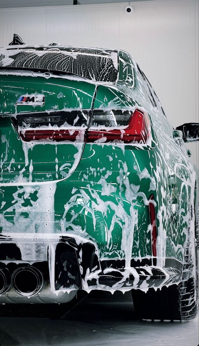 Green BMW rear view covered in foam during deep exterior wash